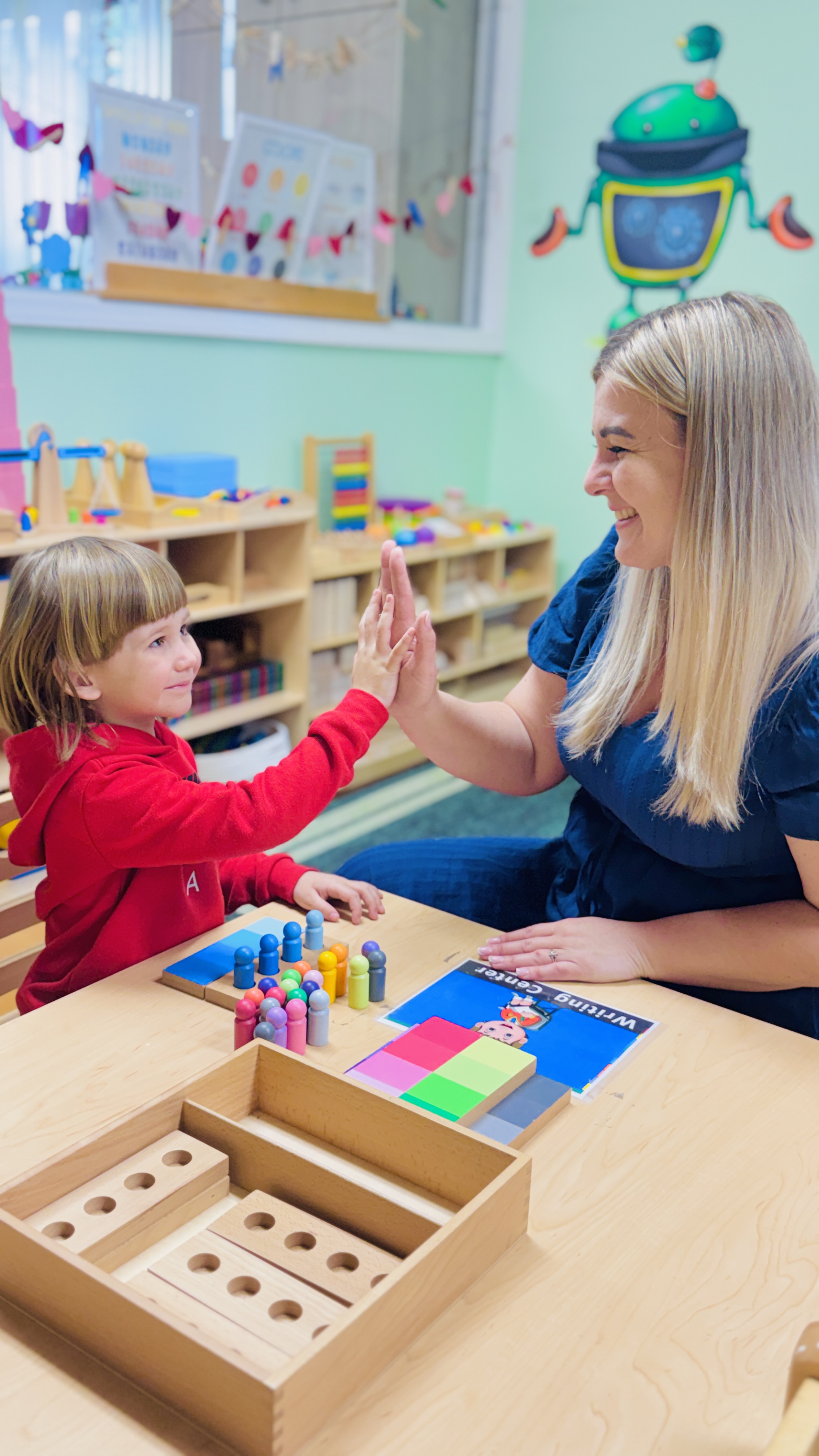 Teacher high-fiving a child during a Montessori work session