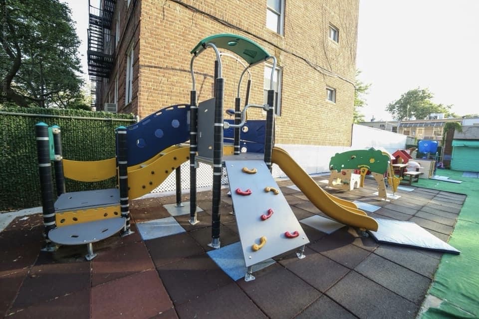 Modern, high-quality playground structure with a climbing ramp and slide on cushioned safety tiles