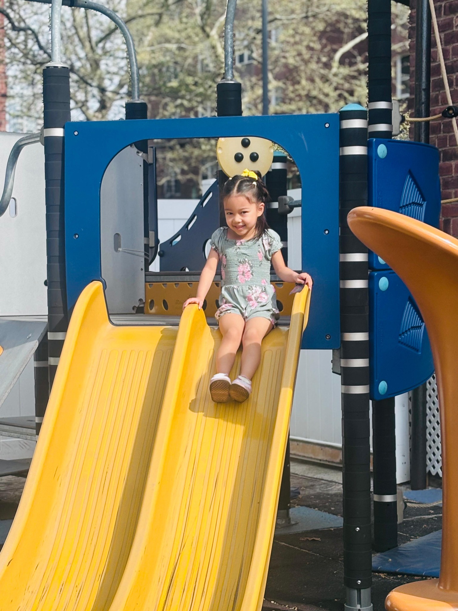 Girl smiling as she slides down the yellow slide