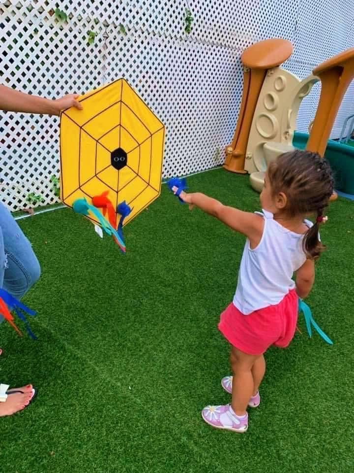 Toddler playing a beanbag toss game outdoors